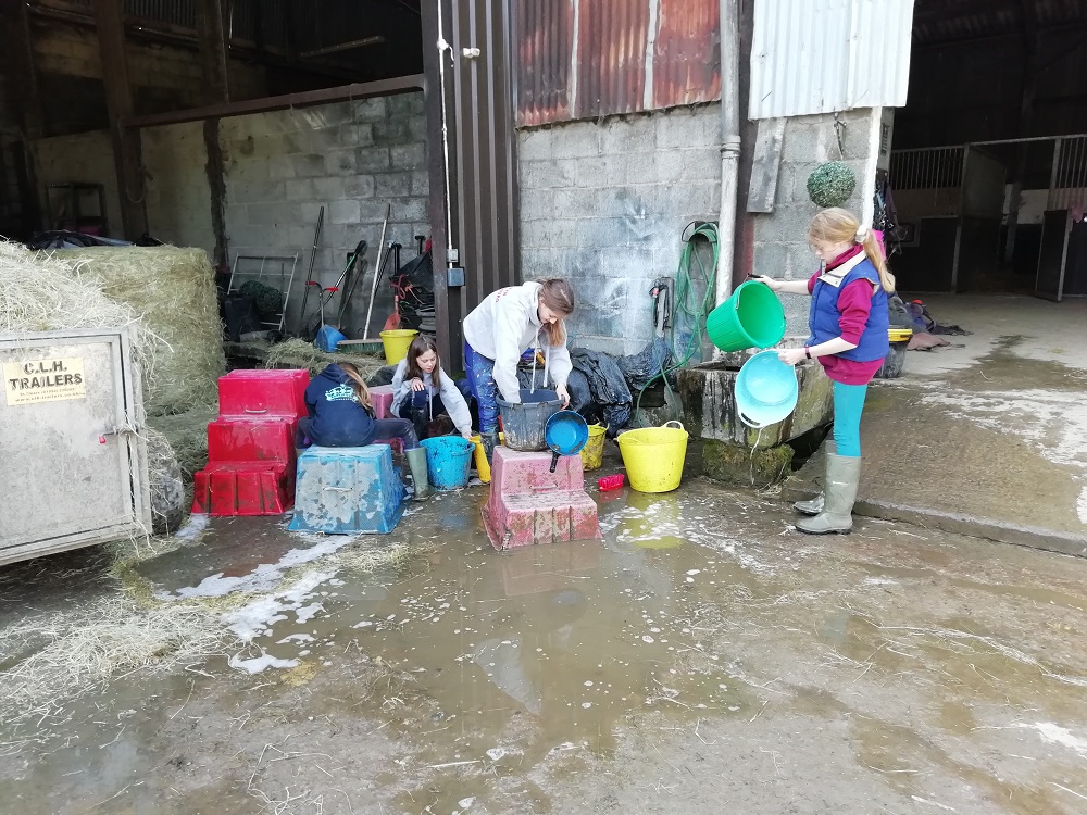 Girls washing up horse buckets 